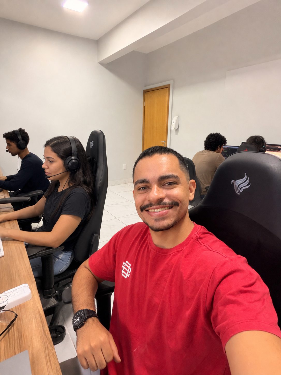 João Farias no escritório, com a equipe trabalhando ao fundo
